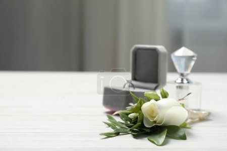 Téléchargez les photos : Des mariages. boutonnière élégante, parfum et anneau sur table en bois blanc, gros plan. Espace pour le texte - en image libre de droit