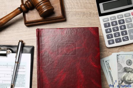 Tax law. Book, calculator, gavel, dollar banknotes and form on wooden table, flat lay