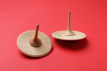Two wooden spinning tops on red background