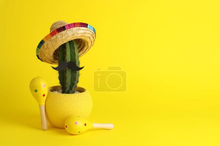 Téléchargez les photos : Cactus avec chapeau de sombrero mexicain, fausse moustache et maracas sur fond jaune, espace pour le texte - en image libre de droit