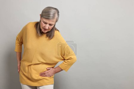 Photo for Arthritis symptoms. Woman suffering from hip joint pain on gray background, space for text - Royalty Free Image