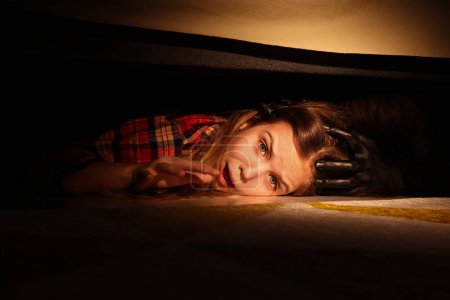 Photo for Childhood phobia. Little girl with monster under bed at home, closeup - Royalty Free Image
