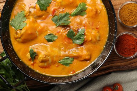 Curry de poulet savoureux avec du persil et des ingrédients sur une table en bois, plat