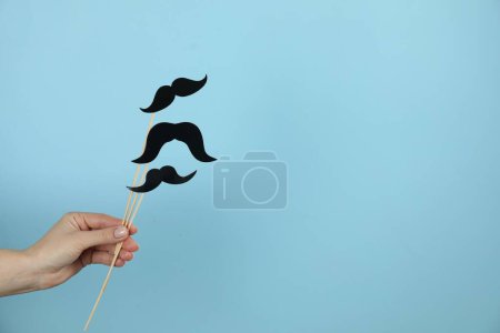 Téléchargez les photos : Femme avec de faux moustaches en papier sur fond bleu clair, gros plan. Espace pour le texte - en image libre de droit