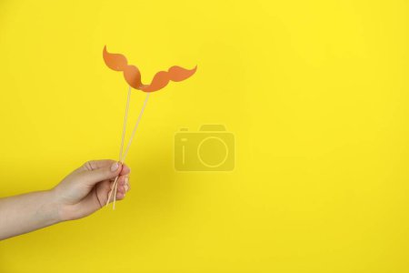 Foto de Mujer con bigotes de papel falsos sobre fondo amarillo, primer plano. Espacio para texto - Imagen libre de derechos