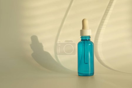 Botella con producto cosmético sobre fondo beige, espacio para texto