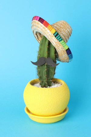 Téléchargez les photos : Cactus avec chapeau de sombrero mexicain et fausse moustache sur fond bleu clair - en image libre de droit