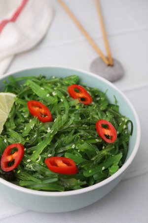 Tasty seaweed salad in bowl served on white table, closeup