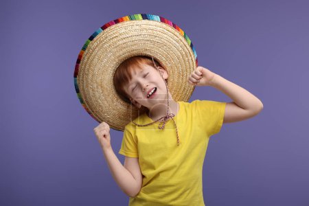 Lindo chico en sombrero mexicano bailando sobre fondo violeta