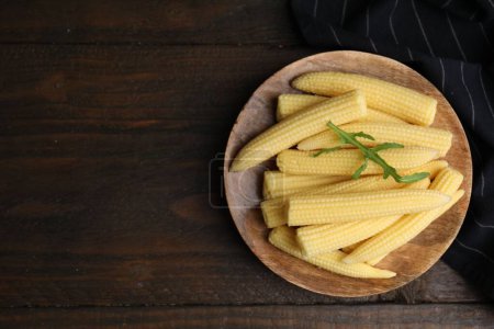 Tasty fresh yellow baby corns on wooden table, top view. Space for text
