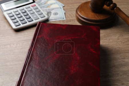 Foto de Derecho fiscal. Libro, calculadora, billetes de dólar y martillo en la mesa de madera, primer plano - Imagen libre de derechos
