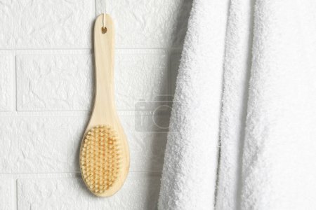 Accesorios de baño. Cepillo de bambú y toalla de rizo en la pared de ladrillo blanco