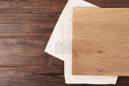 Cutting board and napkin on wooden table, top view. Space for text