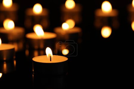 Téléchargez les photos : Brûler des bougies à la surface dans l'obscurité, gros plan. Espace pour le texte - en image libre de droit