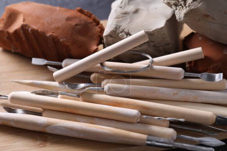 Clay and set of modeling tools on black table, closeup