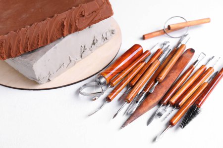 Argile et ensemble d'outils d'artisanat sur table texturée blanche, gros plan