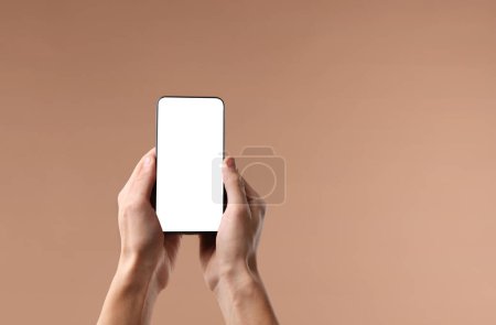 Mann hält Smartphone mit leerem Bildschirm auf beigem Hintergrund, Nahaufnahme. Mockup für Design