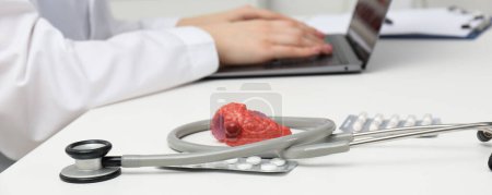 Endocrinologist working at table, focus on stethoscope and model of thyroid gland. Banner design