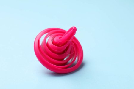 One pink spinning top on light blue background, closeup