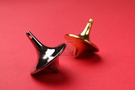 Golden and silver spinning tops on red background, closeup