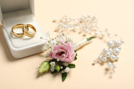 Téléchargez les photos : Des mariages. boutonnière élégante, anneaux et décor sur fond beige, gros plan - en image libre de droit
