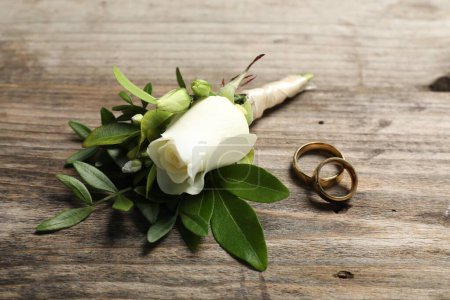 Téléchargez les photos : Des mariages. Boutonnière élégante et anneaux sur table en bois, gros plan - en image libre de droit