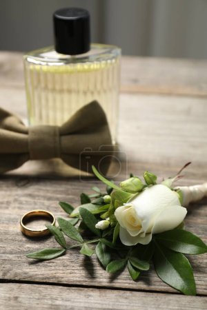 Téléchargez les photos : Des mariages. boutonnière élégante, parfum, noeud papillon et anneau sur table en bois, gros plan - en image libre de droit