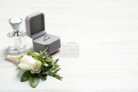 Téléchargez les photos : Des mariages. boutonnière élégante, parfum et anneau sur table en bois blanc, gros plan. Espace pour le texte - en image libre de droit
