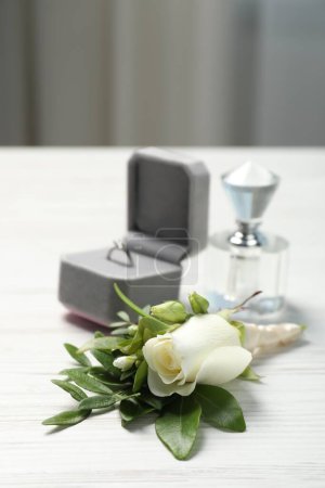 Téléchargez les photos : Des mariages. boutonnière élégante, parfum et anneau sur table en bois blanc, gros plan - en image libre de droit