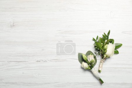 Téléchargez les photos : Des mariages. Boutonnières élégantes sur table en bois blanc, vue sur le dessus. Espace pour le texte - en image libre de droit