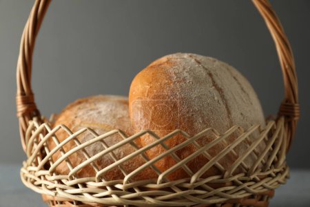Wicker basket with fresh bread on grey table, closeup