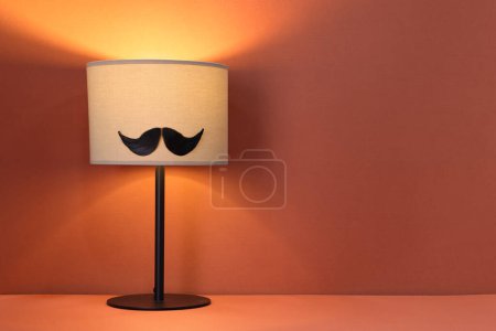 Téléchargez les photos : Visage d'homme en moustache artificielle et lampe sur fond terre cuite. Espace pour le texte - en image libre de droit