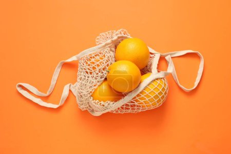 Téléchargez les photos : Sac à ficelle avec des oranges fraîches sur fond de couleur, vue de dessus - en image libre de droit