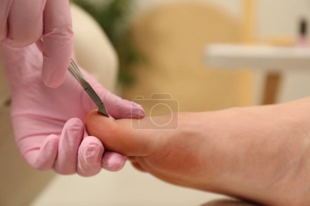 Photo for Professional pedicurist cutting client`s toenails with clipper in beauty salon, closeup - Royalty Free Image
