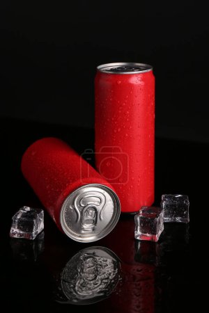 Foto de Bebidas energéticas en latas mojadas y cubitos de hielo sobre fondo negro - Imagen libre de derechos