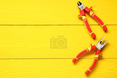 Photo for Pliers on yellow wooden table, flat lay. Space for text - Royalty Free Image