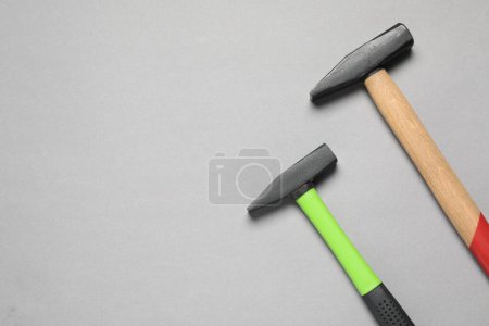 Two hammers on grey background, top view. Space for text