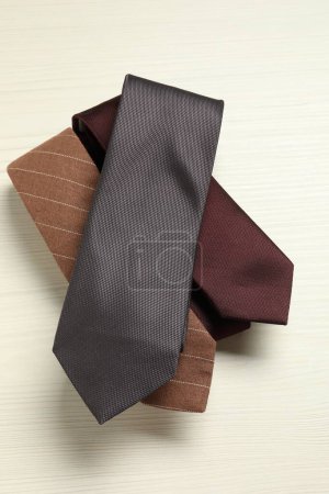 Different neckties on white wooden table, top view