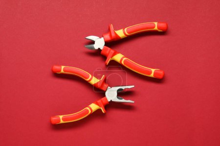 Photo for Two pliers on red background, flat lay - Royalty Free Image