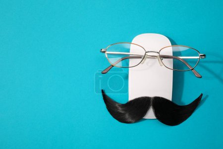 Téléchargez les photos : Moustache artificielle, souris d'ordinateur et lunettes sur fond bleu clair, vue de dessus. Espace pour le texte - en image libre de droit