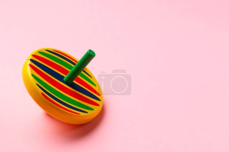 One colorful spinning top on pink background, space for text