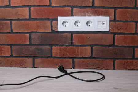 Enchufe eléctrico y tomas de corriente en la pared de ladrillo