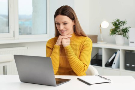 Foto de Mujer que tiene chat de vídeo a través de ordenador portátil en la mesa en la oficina - Imagen libre de derechos