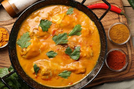 Curry de poulet savoureux avec du persil et des ingrédients sur une table en bois, plat