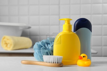 Foto de Productos cosméticos para bebés, pato de baño, cepillo y hisopos de algodón sobre mesa blanca - Imagen libre de derechos