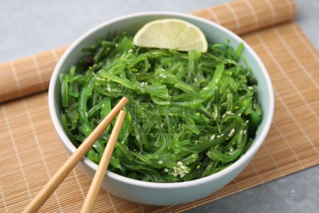Tasty seaweed salad in bowl served on gray table, closeup
