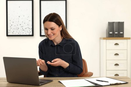 Foto de Mujer teniendo chat de vídeo a través de ordenador portátil en la mesa de madera en la oficina - Imagen libre de derechos