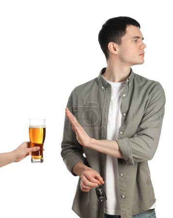 Téléchargez les photos : Homme avec des clés de voiture refusant l'alcool tandis que la femme lui suggérant de la bière sur fond blanc, gros plan. Ne pas boire et conduire concept - en image libre de droit