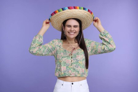 Mujer joven en sombrero mexicano sobre fondo violeta