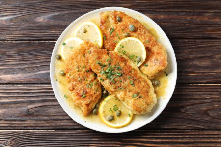 Delicious chicken piccata on wooden table, top view